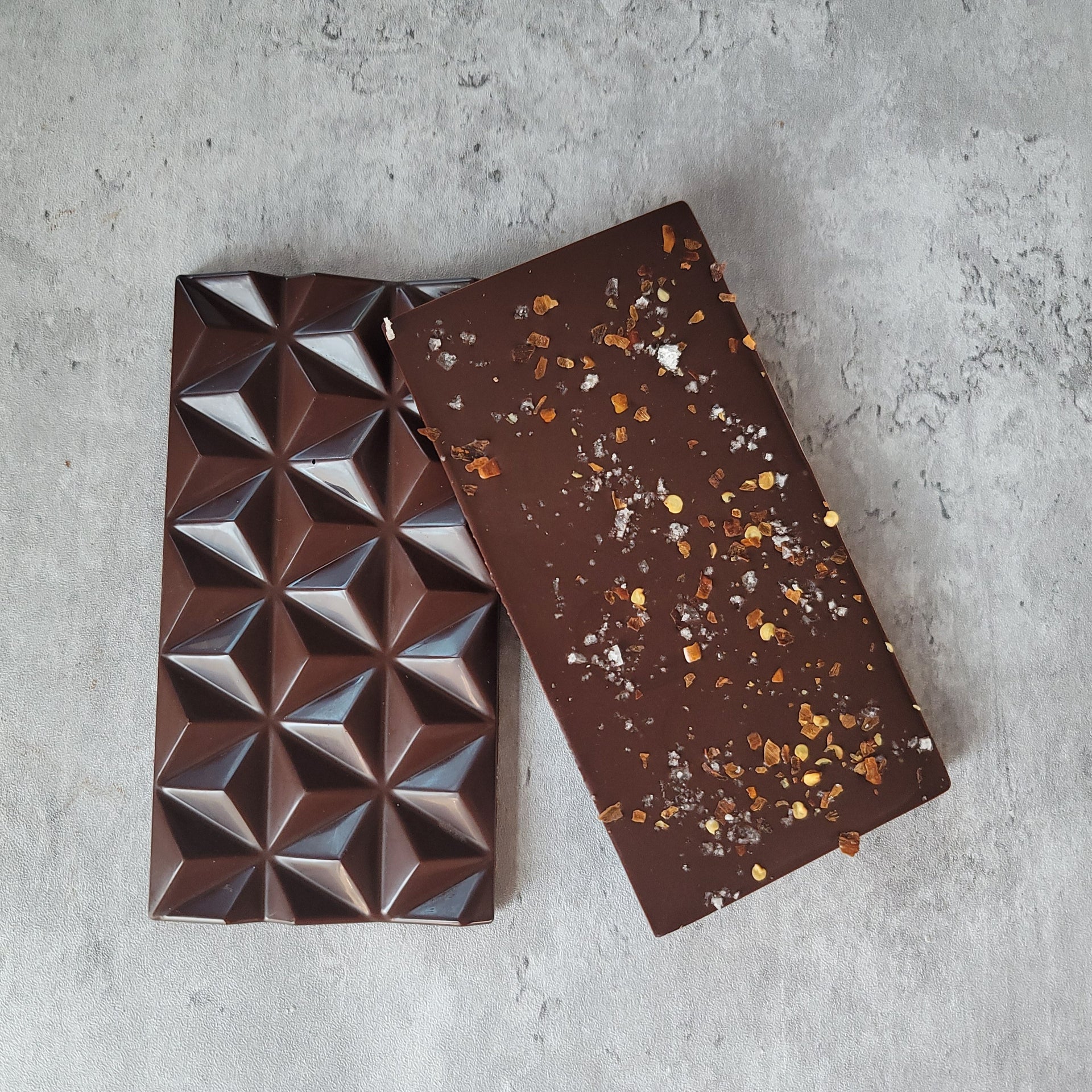 Photo of both sides of the chocolate bar. Chili flakes and smoked salt  are sprinkled on one side. 